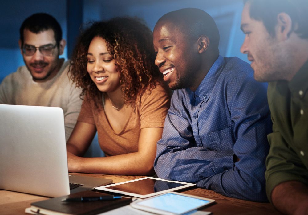 The group of young adults use a laptop